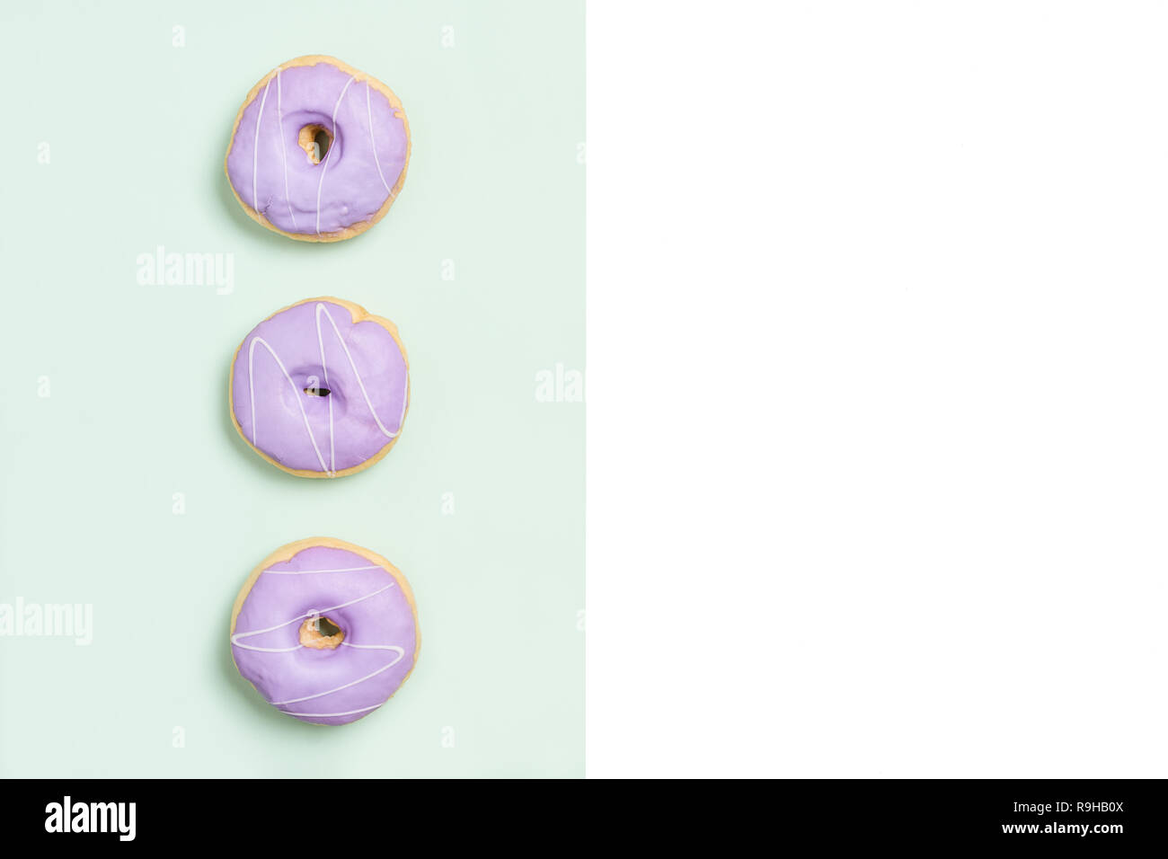Three purple donuts on split color background modern design with copy space. Stock Photo