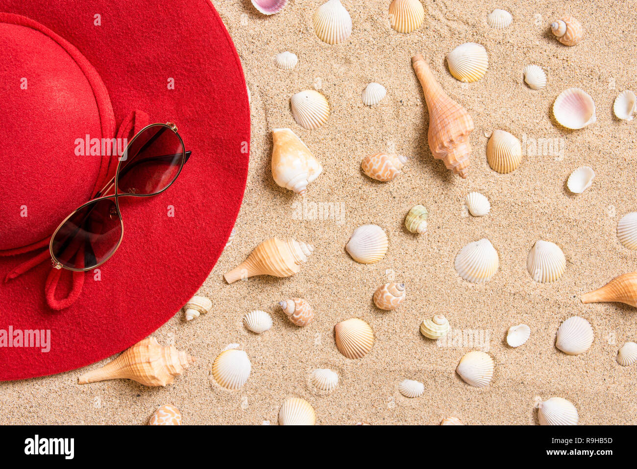 red hat on sandy beach with sunglasses, seashells and copy space for text. Stock Photo