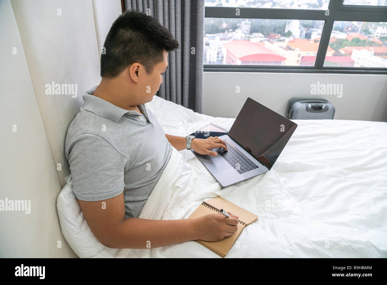 Young man search information on Internet and take notes Stock Photo