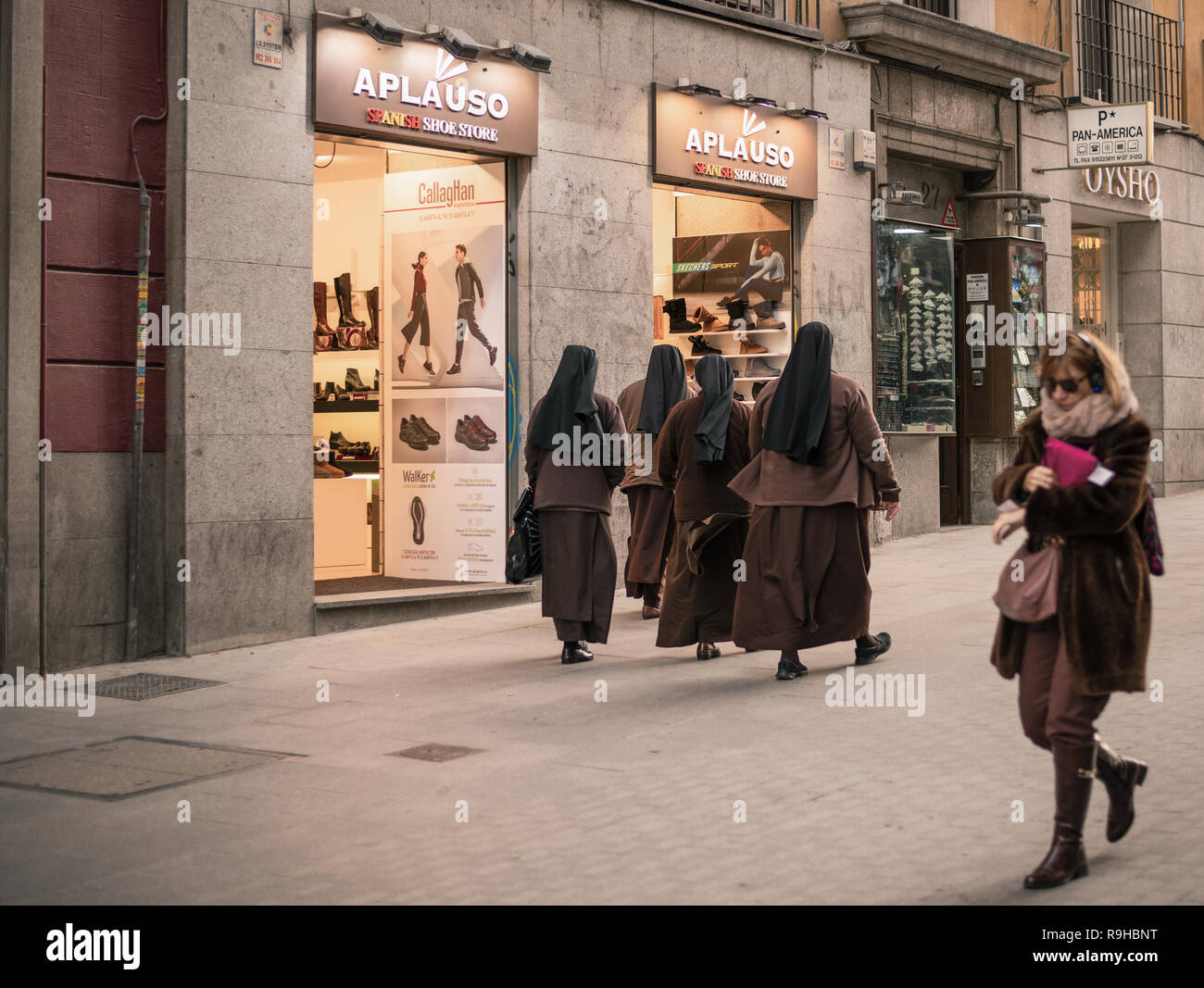 group of nuns walking down the street while looking at clothing and footwear stores Stock Photo