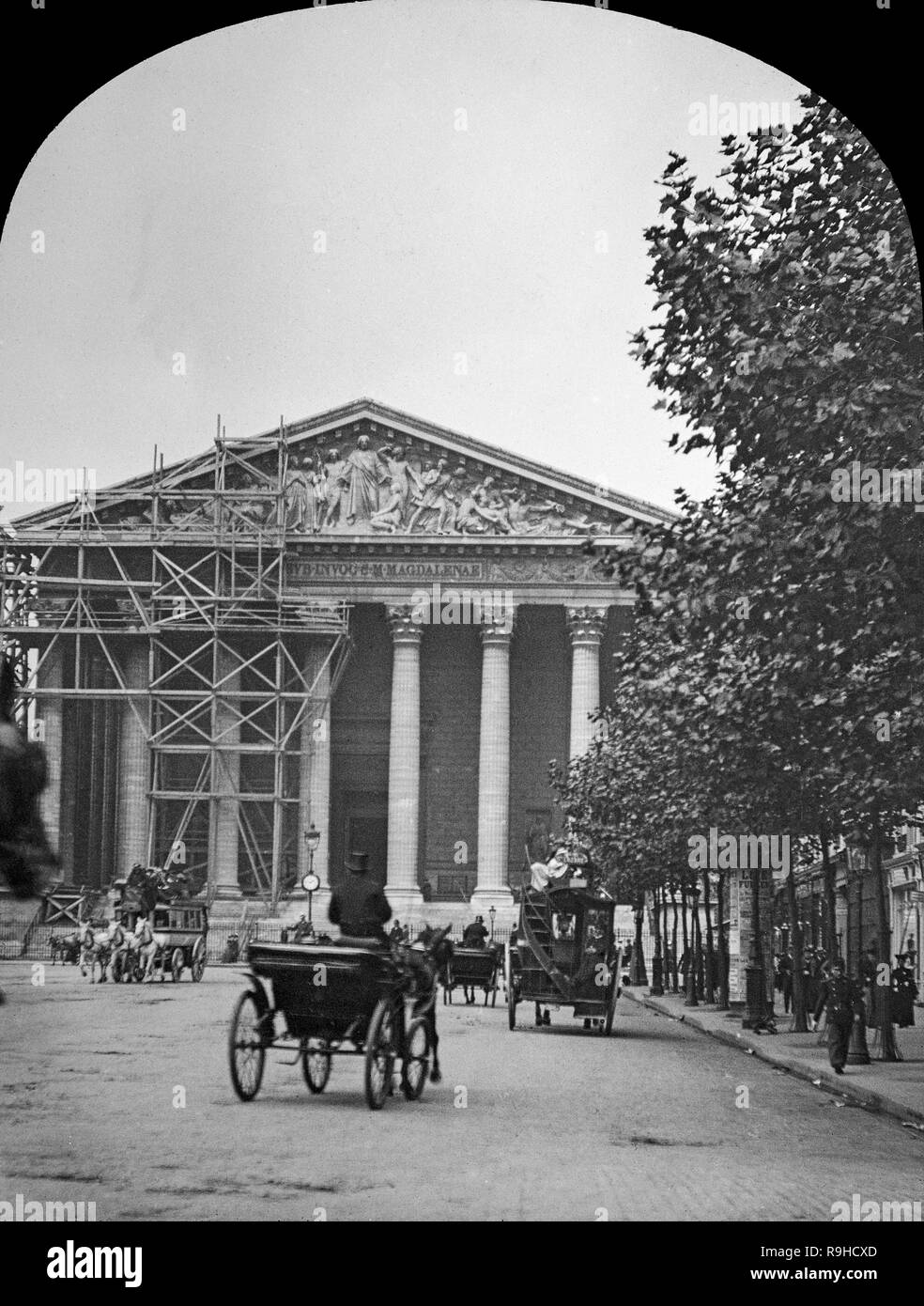 A late Victorian black and white photograph showing L'église de la Madeleine in Paris. It is a Roman Catholic church occupying a commanding position in the 8th arrondissement of Paris. The Madeleine Church was designed in its present form as a temple to the glory of Napoleon's army. To its south lies the Place de la Concorde, to the east is the Place Vendôme, and to the west Saint-Augustin, Paris. It's construction started in 1764, but was not finished until 1842. Image shows horse drawn carriages and people. Also shows scaffolding in place for work to be carried out. Stock Photo