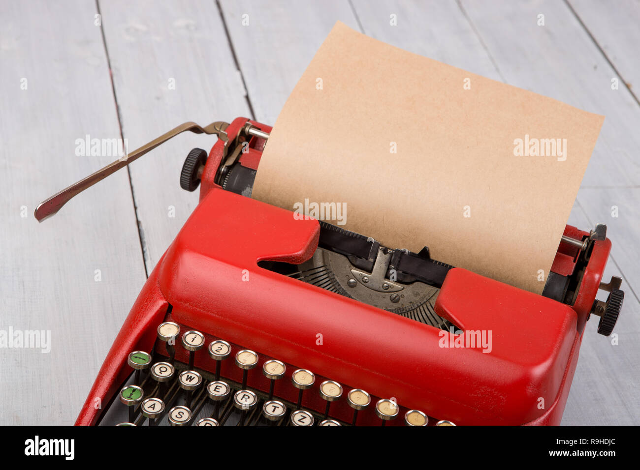 Red vintage typewriter with blank paper sheet on white wooden table Stock Photo