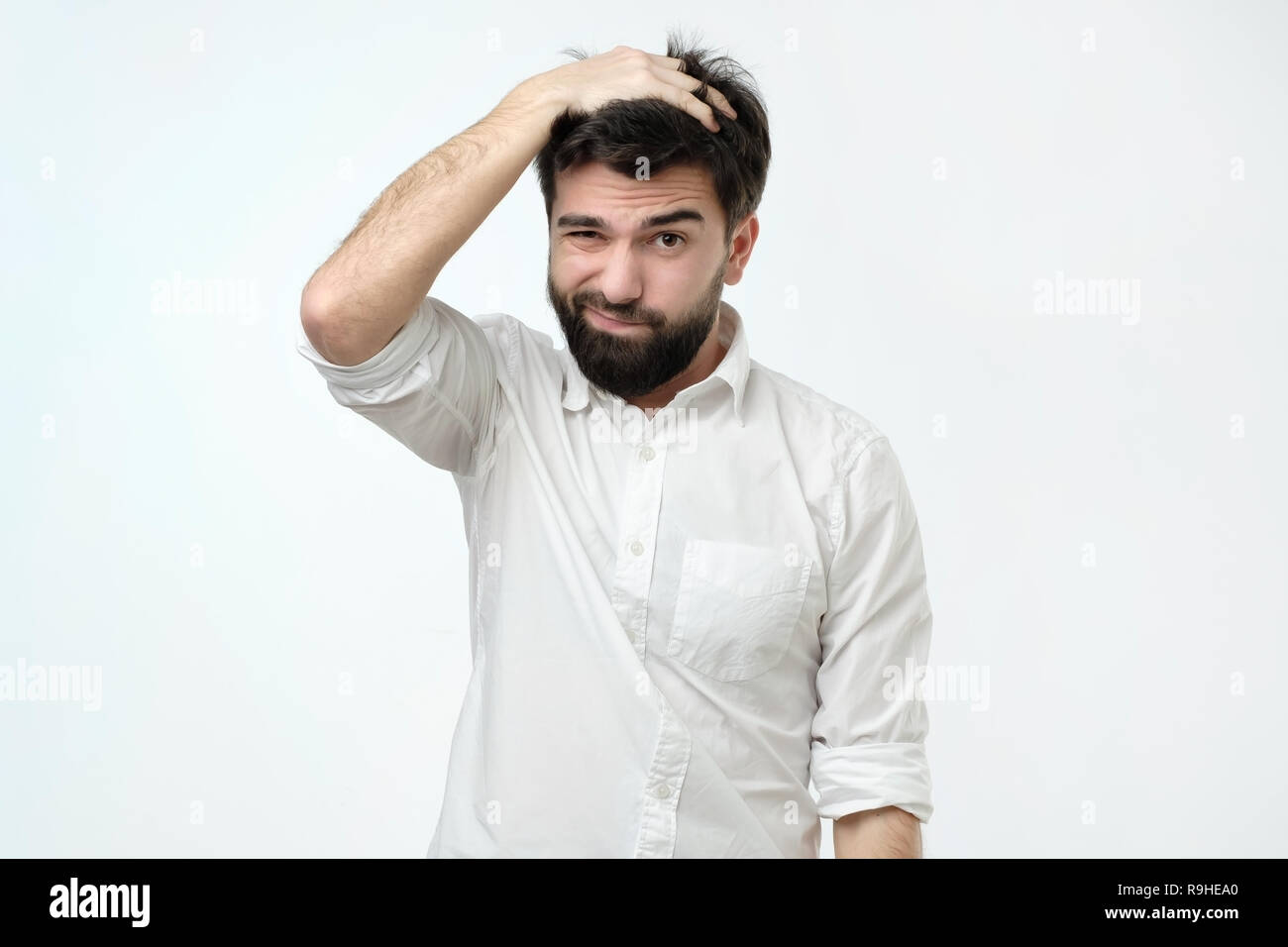 Hispanic man with beard looking with puzzled expression, scratching head, being clueless Stock Photo