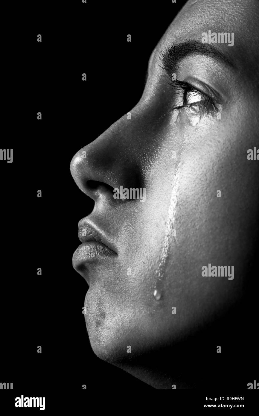 sad woman crying, looking up on black background, closeup portrait, profile view Stock Photo