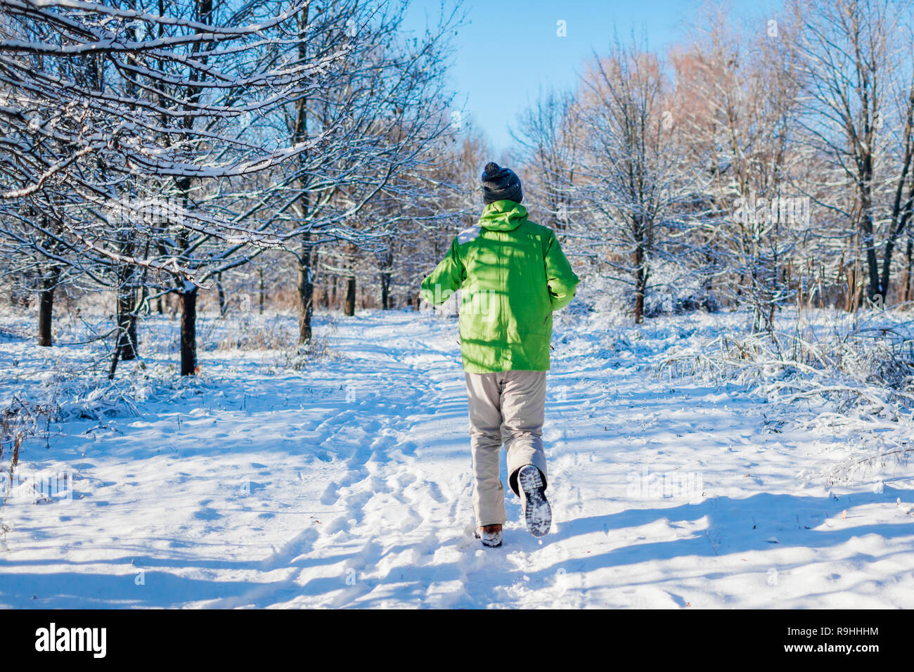 Running athlete man sprinting in winter forest. Training outside in cold snowy weather. Active healthy lifestyle Stock Photo