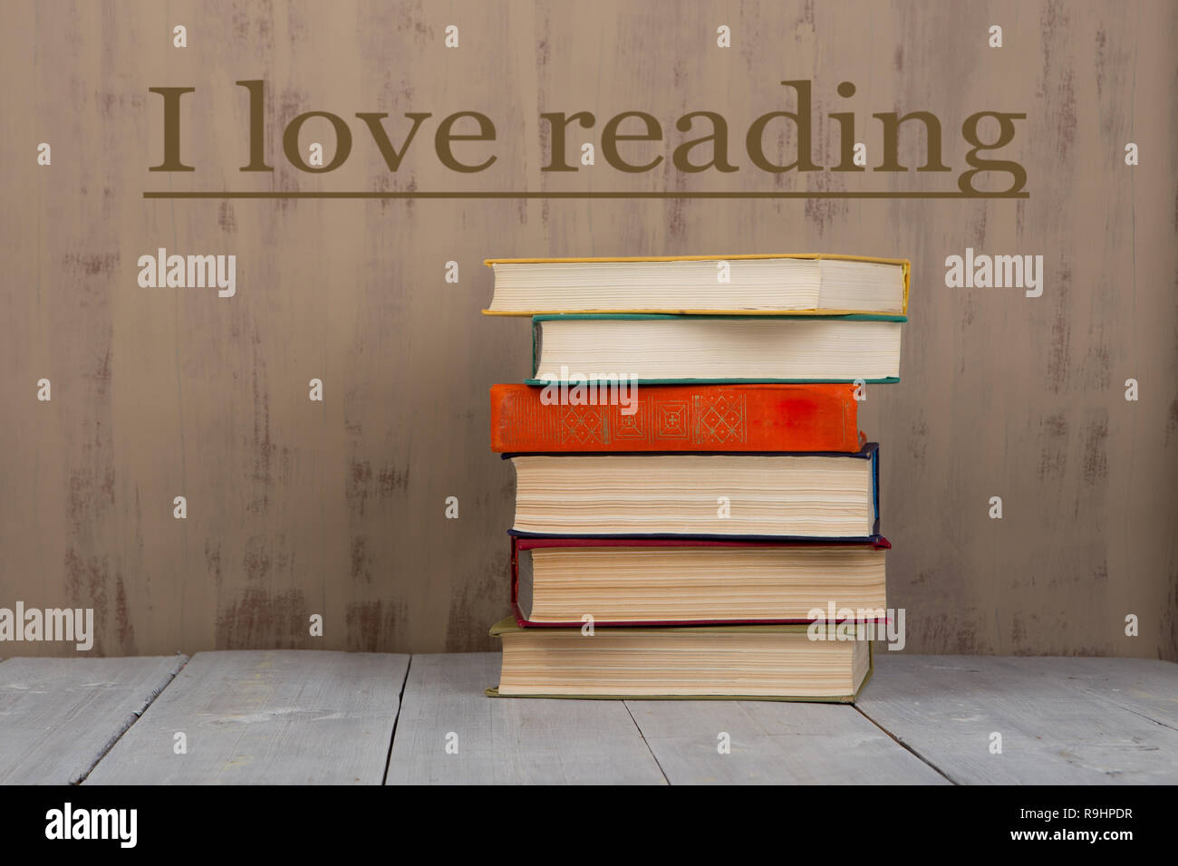 Back to school and education concept - heap colorful hardback books on white wooden table on brown background with text 'I love reading' Stock Photo