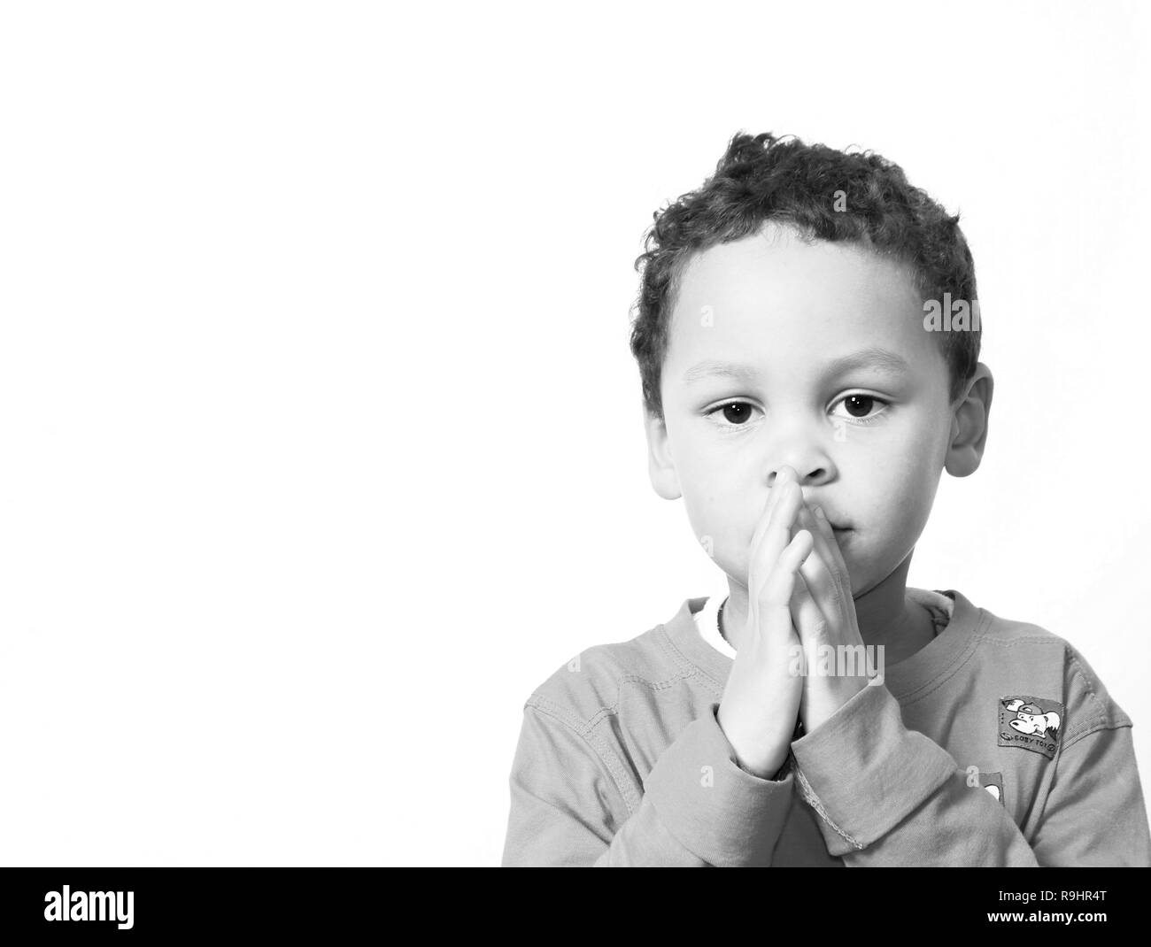 boy praying to God with hands held together with closed eyes stock