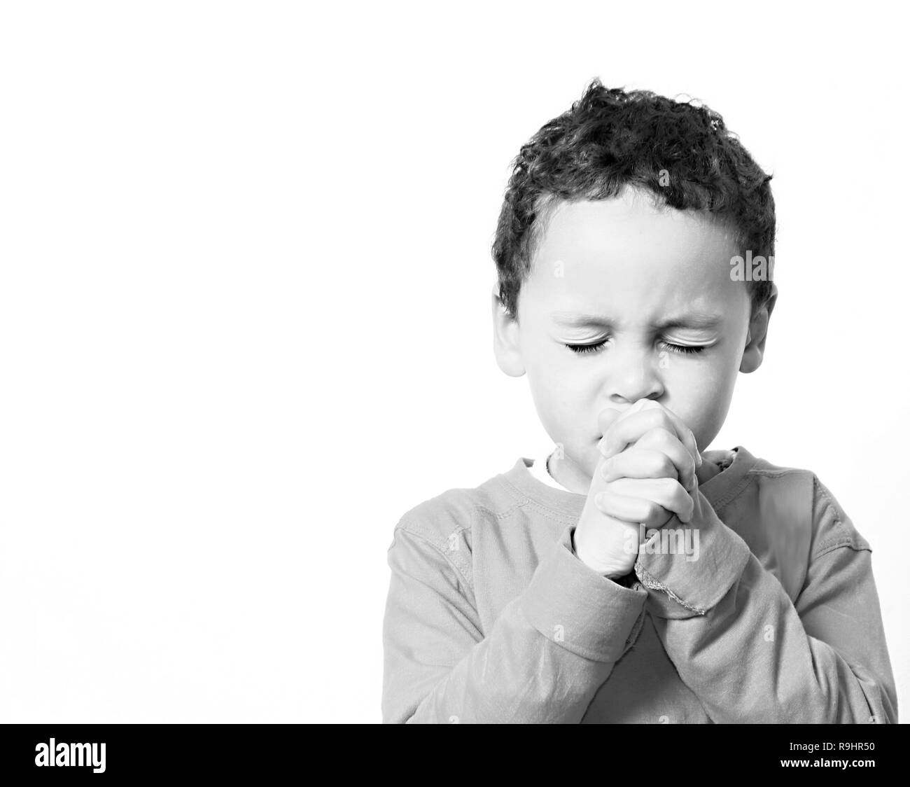 boy praying to God with hands held together with closed eyes stock