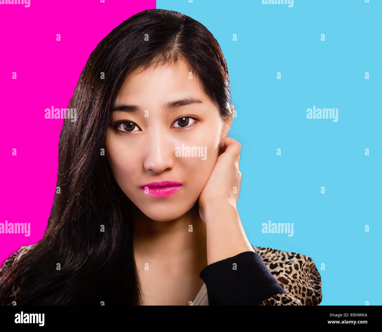 Asian fashion model with hand on face pink and turquoise background Stock Photo