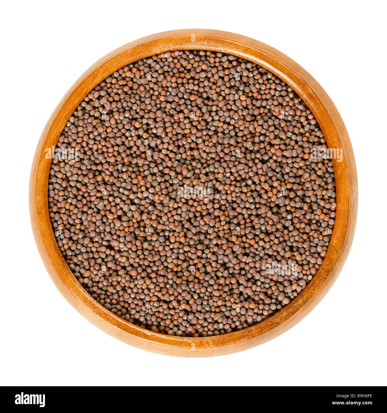 Black mustard seeds in wooden bowl. Brassica nigra with black and dark brown seeds. Used for making mustard, sprouting, as a spice and as a condiment. Stock Photo