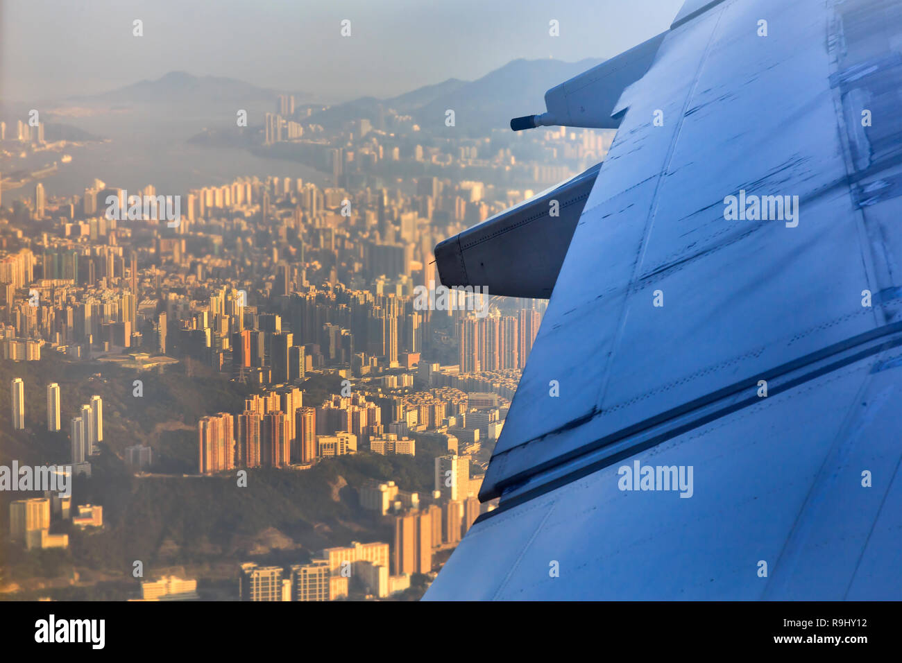 Mid-air view down on over developed islands of Hong Kong with airplane wing in a sight seen out of passenger window. Stock Photo