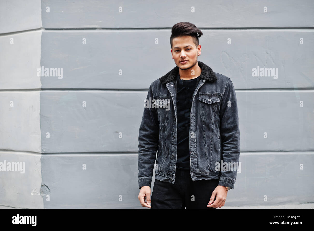 Handsome and fashionable indian man in black jeans jacket posed against  gray wall Stock Photo - Alamy