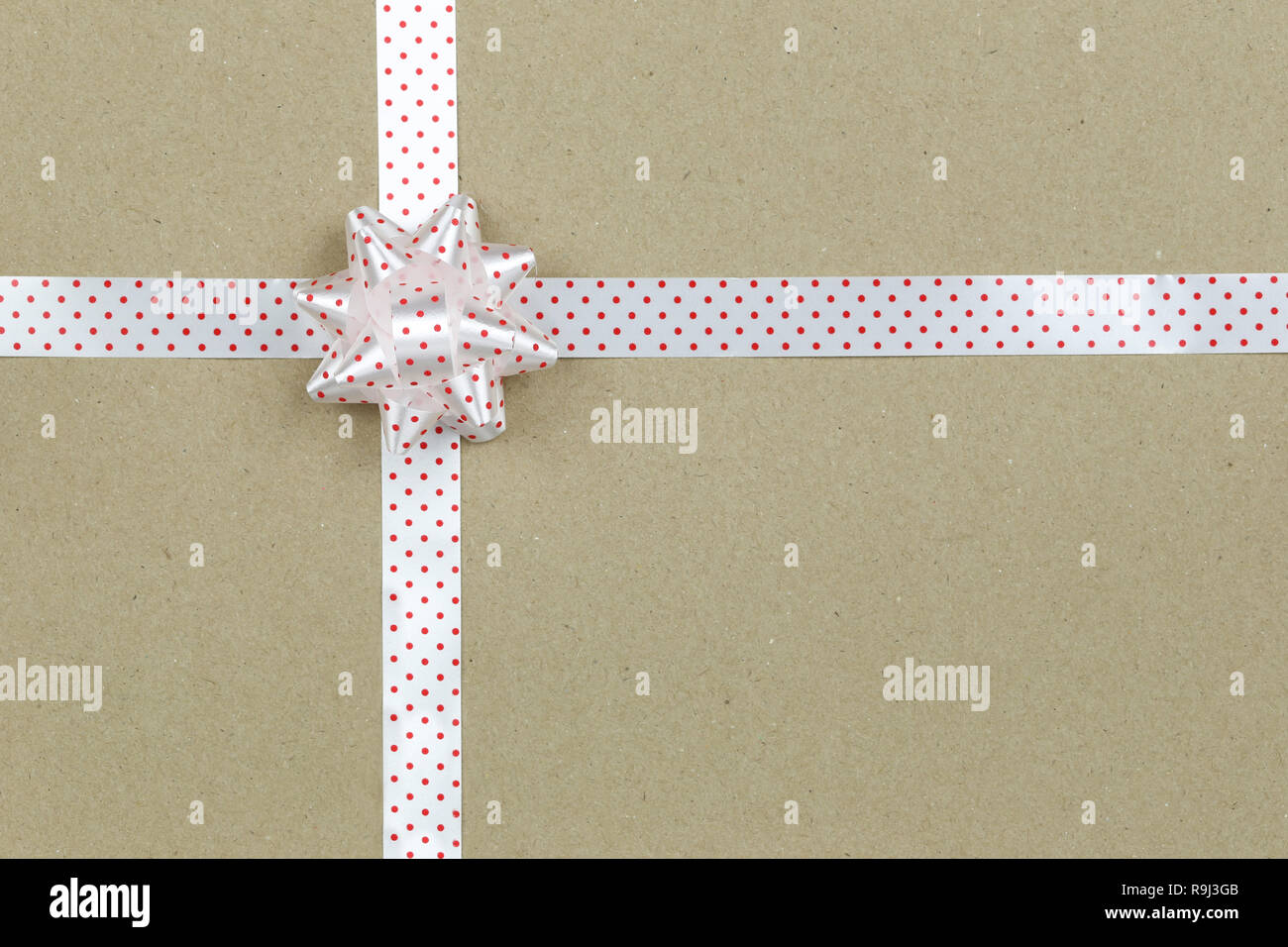 Christmas Bow And Ribbon On Brown Paper Background Top View On Gift Box christmas-bow-and-ribbon-on-brown-paper-background-top-view-on-gift-box