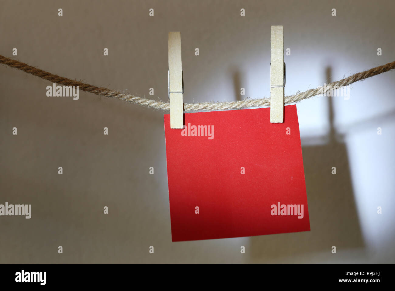 Red note paper hanging on rope on white wall and have clipping paths. Stock Photo