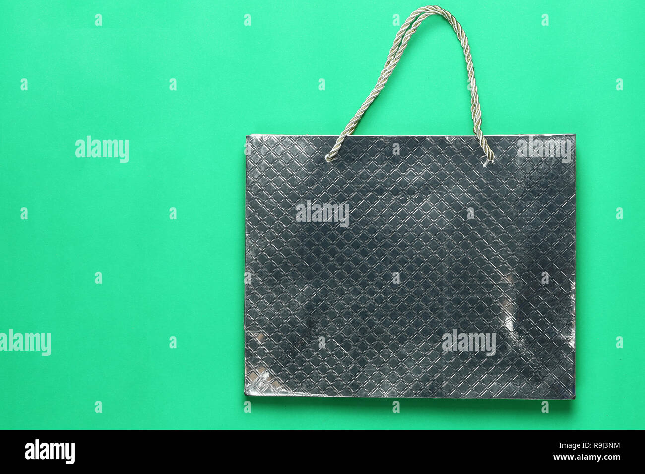 Silver shopping paper bag on green background and have copy space for design in your concept. Stock Photo
