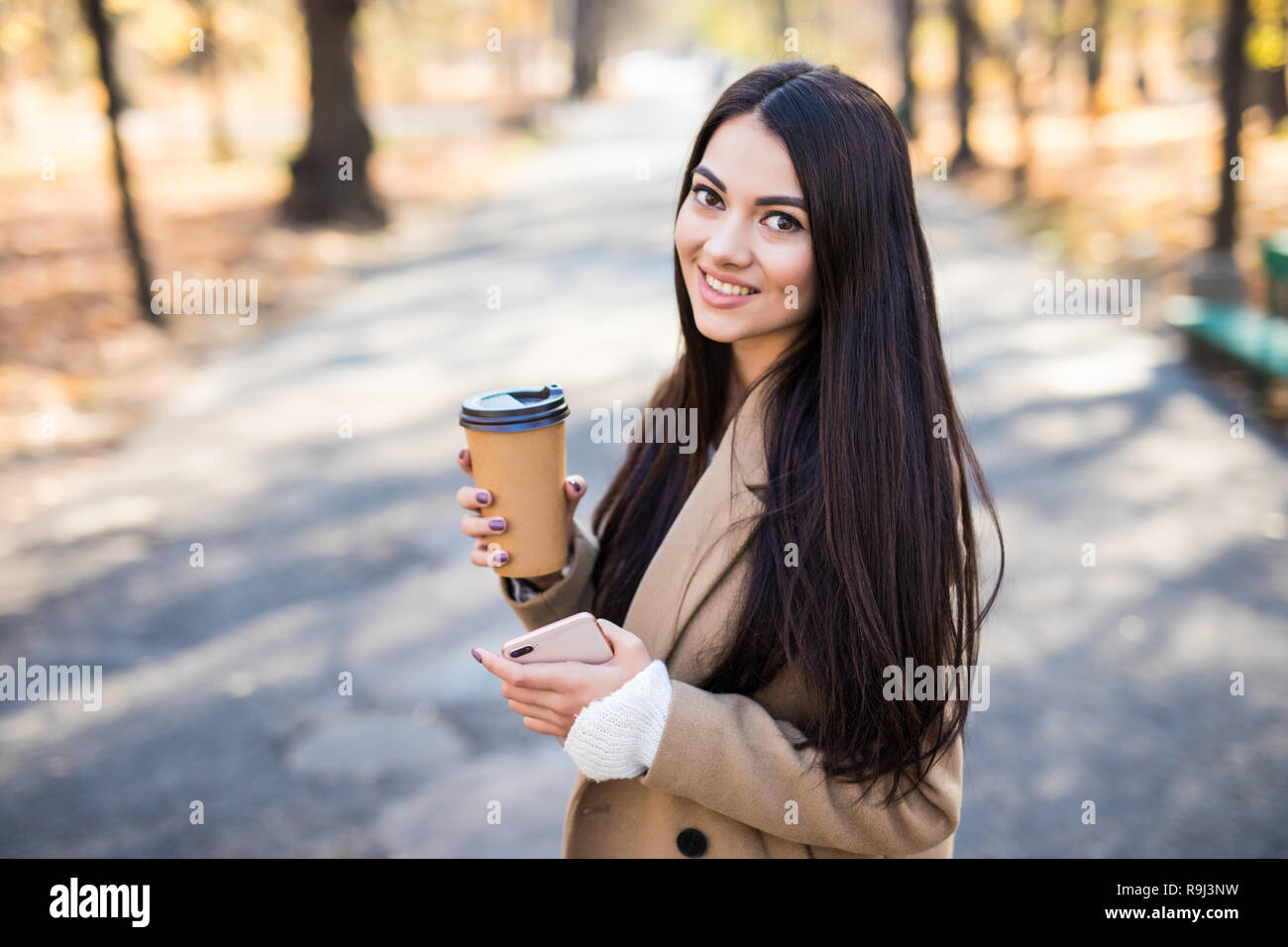 Pretty woman with coffee cup in the autumn park Stock Photo - Alamy
