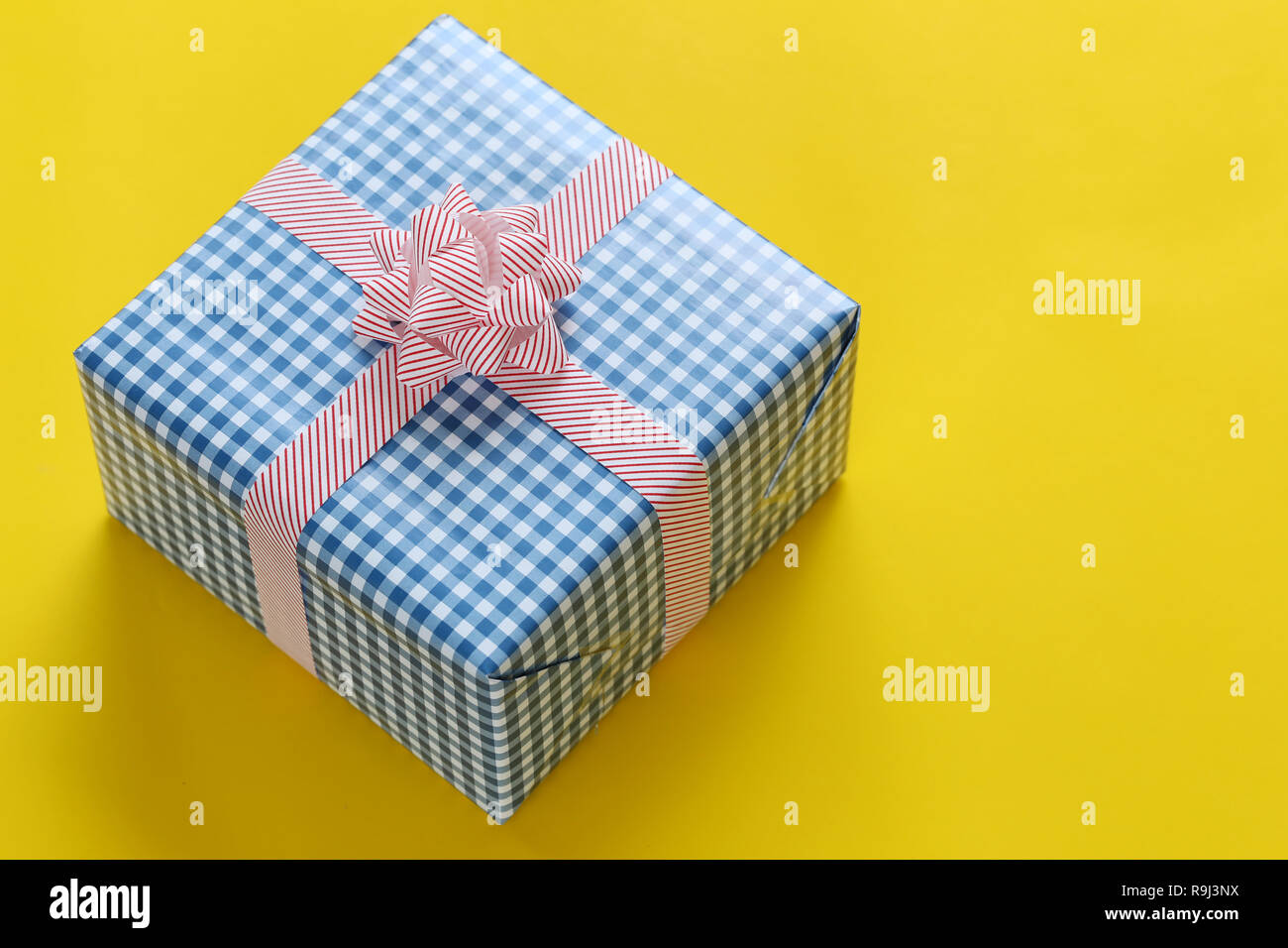 Blue Christmas gift box placed on a yellow art paper floor and have copy space for design in your work Important day concept. Stock Photo
