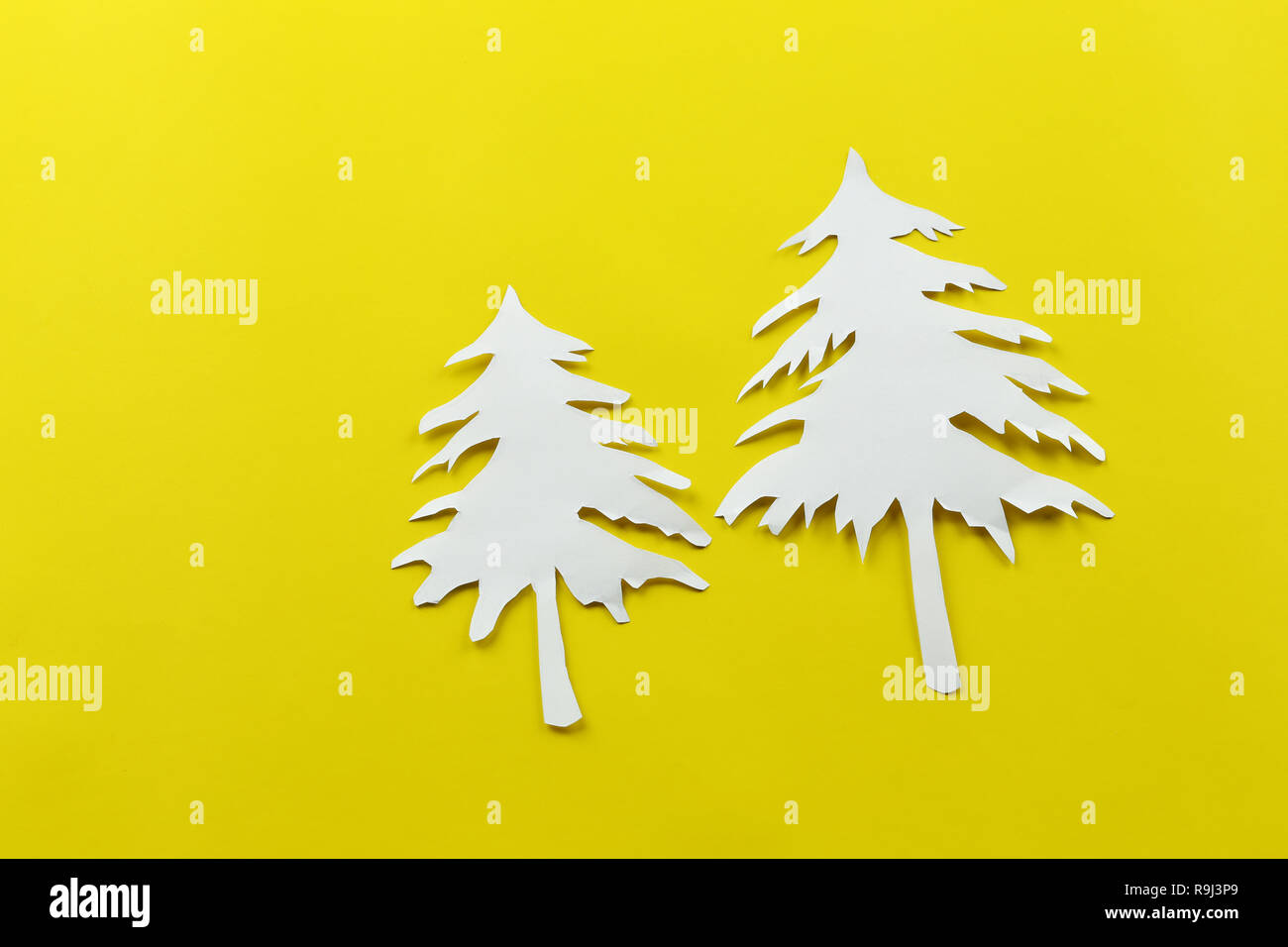 Christmas tree shape of white paper on yellow paper background for design in your festival concept. Stock Photo