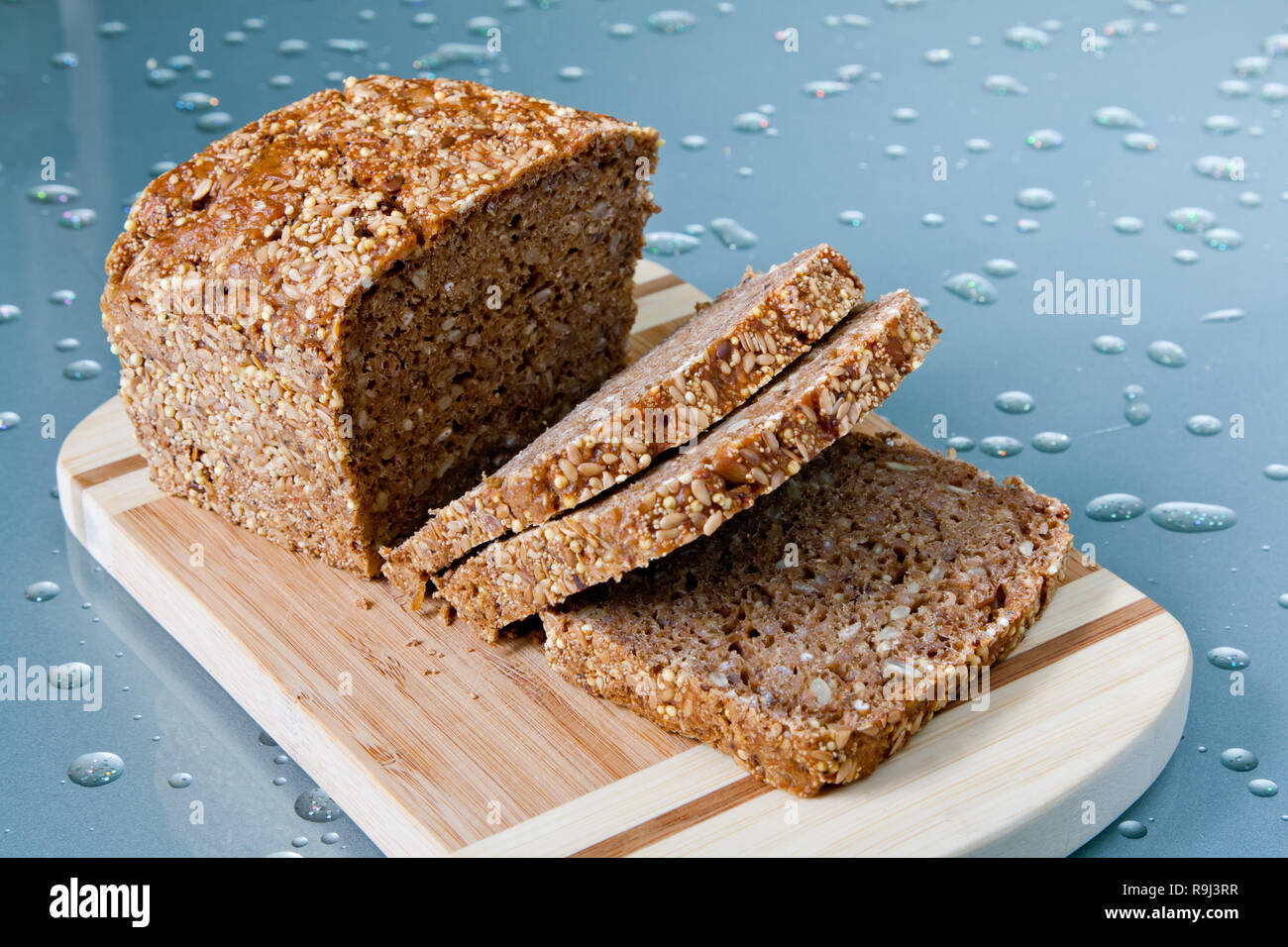 Loaf of wholegrain bread and slices on wooden cutting board. Healthy food Stock Photo