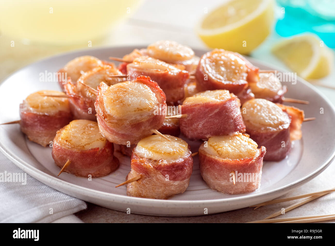 A plate of delicious bacon wrapped scallops with lemon. Stock Photo