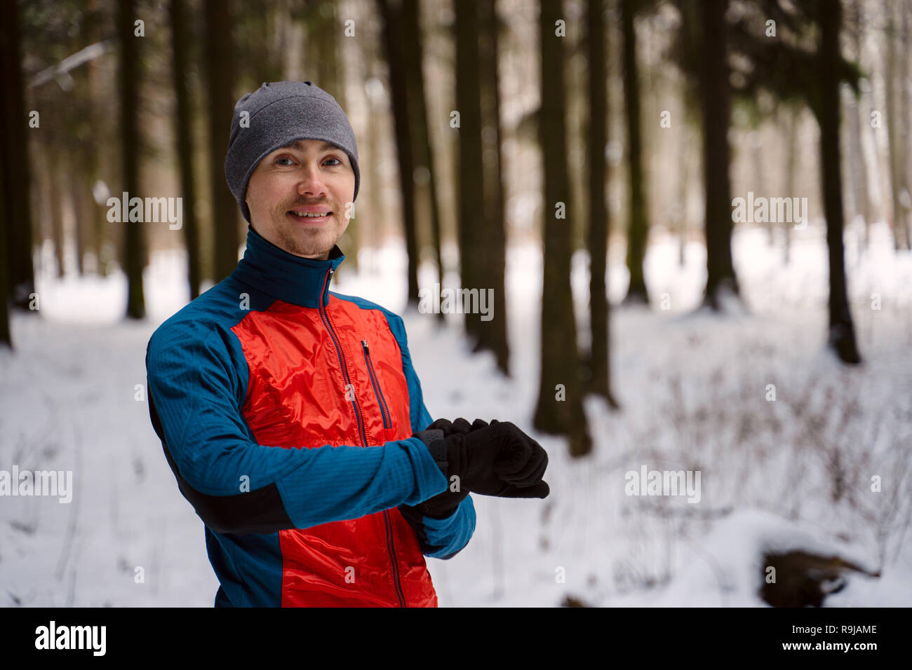 Runner wearing warm sporty clothes looks at a modern smart clock and counts up spent calories Stock Photo