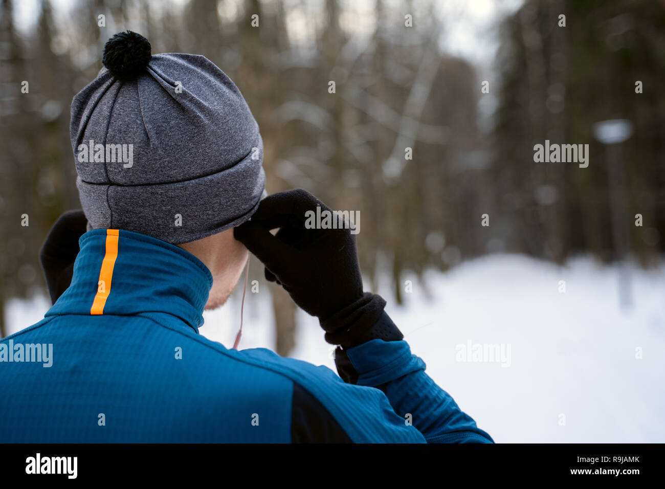 Portrait of a runner from the back wearing headphones and preparing to run in the winter forest Stock Photo