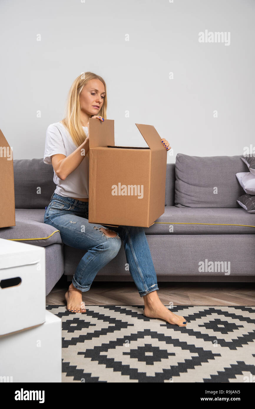 Image of young woman with cardboard box sitting on sofa Stock Photo - Alamy