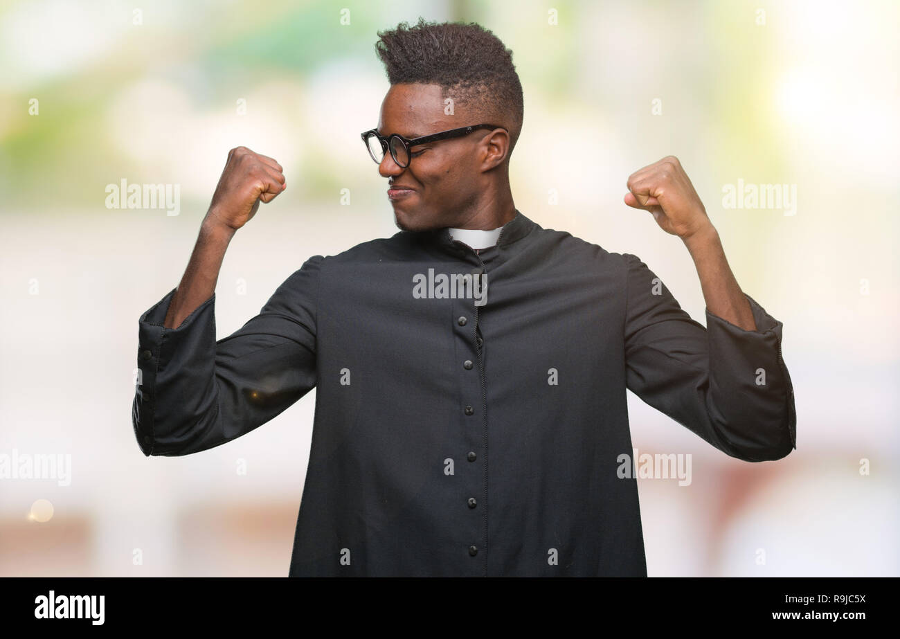 Young african american priest man over isolated background showing arms muscles smiling proud. Fitness concept. Stock Photo