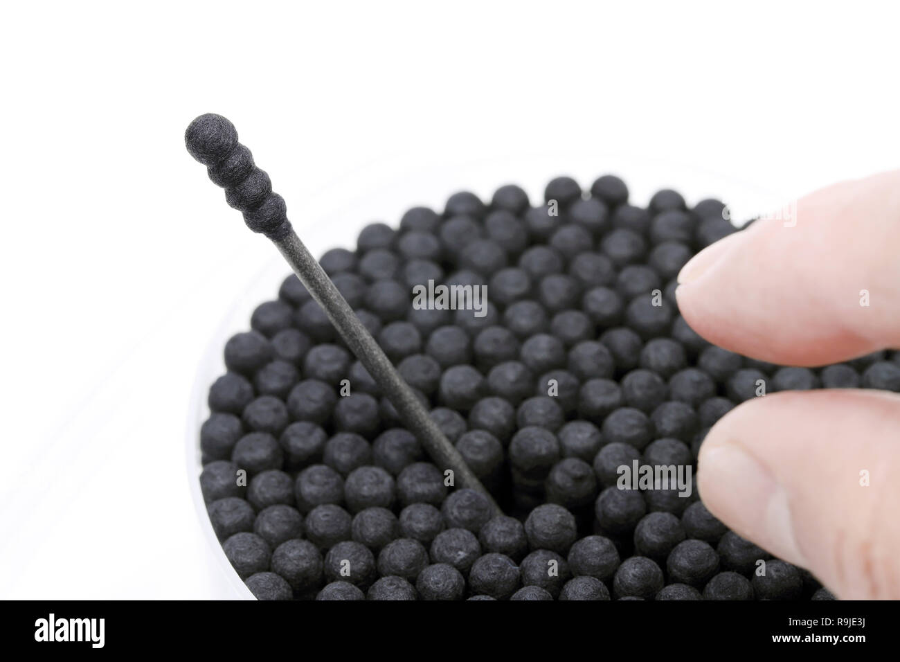 Black cotton swabs with the finger on the white background Stock Photo
