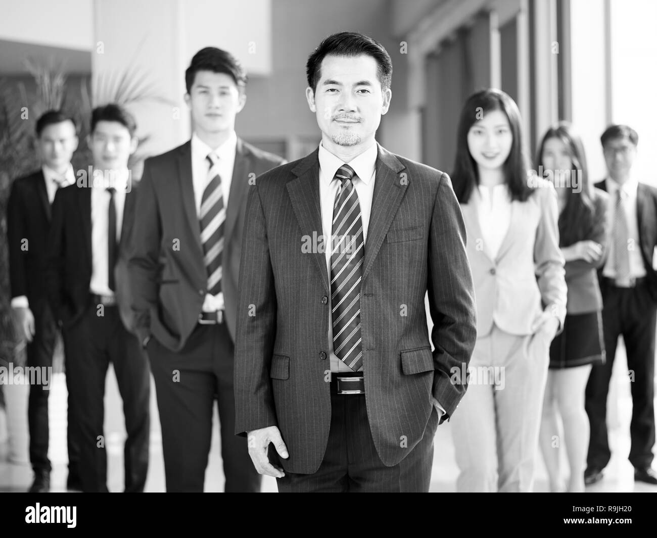portrait of a team of successful asian businessmen and businesswomen, looking at camera, black and white. Stock Photo