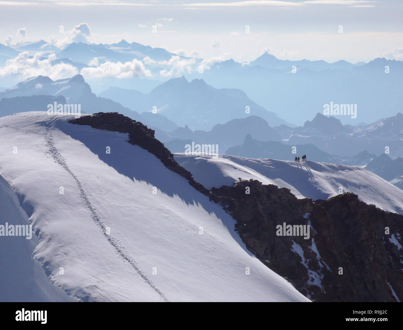 high alpine mountain peak with four climbers heading to the top and a ...