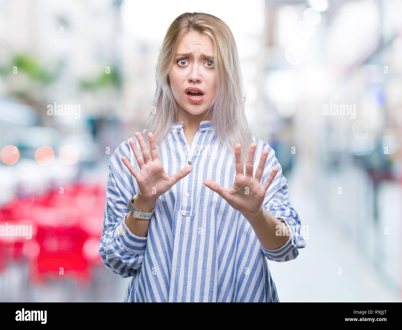 Young blonde woman over isolated background afraid and terrified with fear expression stop gesture with hands, shouting in shock. Panic concept. Stock Photo