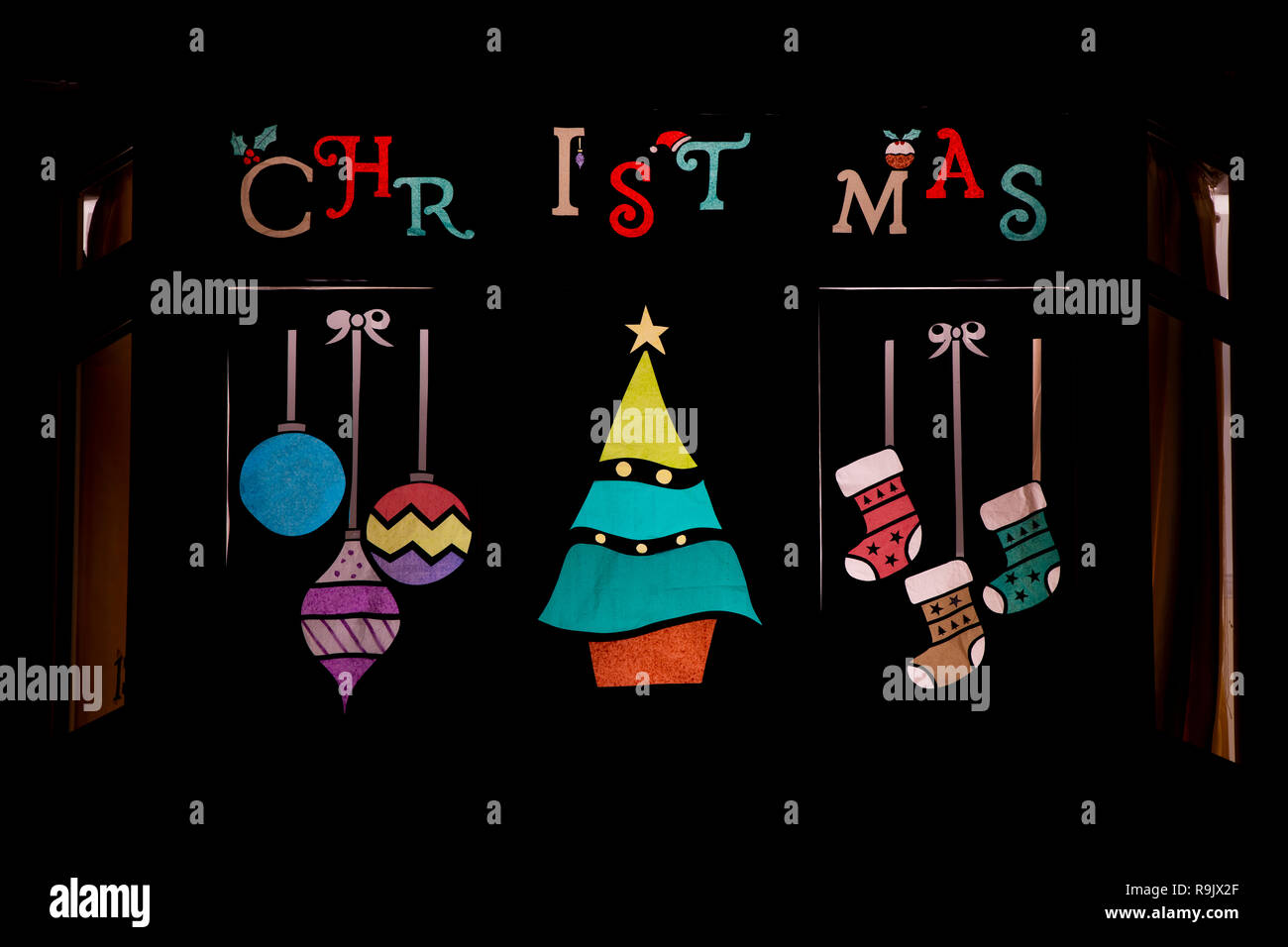 Festive Christmas window display. Christmas tree, stockings and baubles. Northamptonshire, England Stock Photo