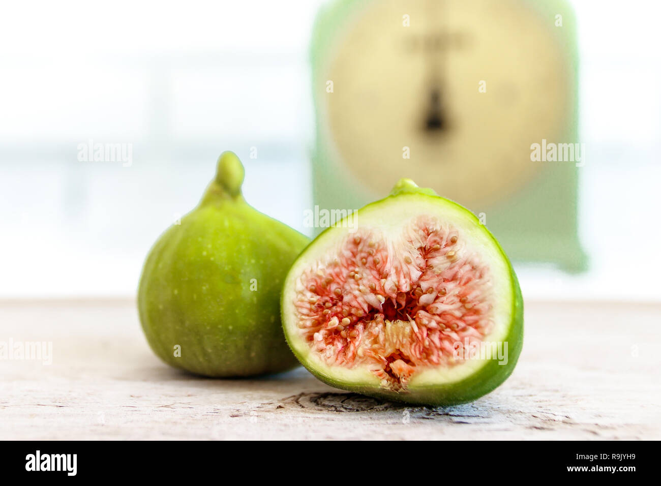 Retro / antique kitchen scale and ripe, halved figs on natural wood table Stock Photo