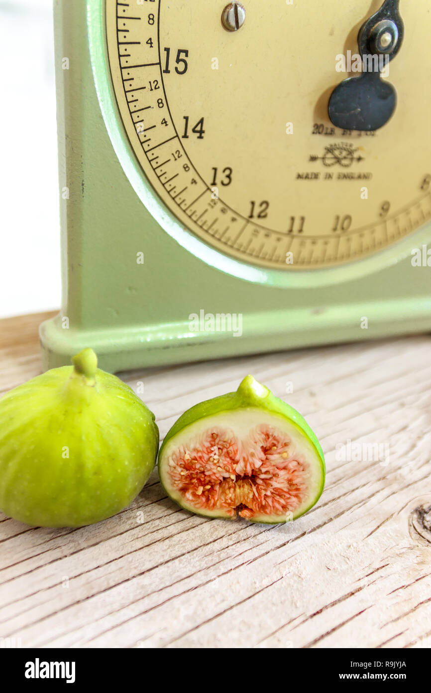 Retro / antique kitchen scale and ripe, halved figs on natural wood table Stock Photo
