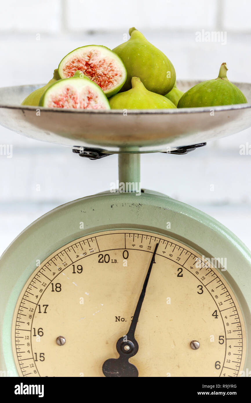 Retro / antique kitchen scale and ripe, halved figs on natural wood table Stock Photo