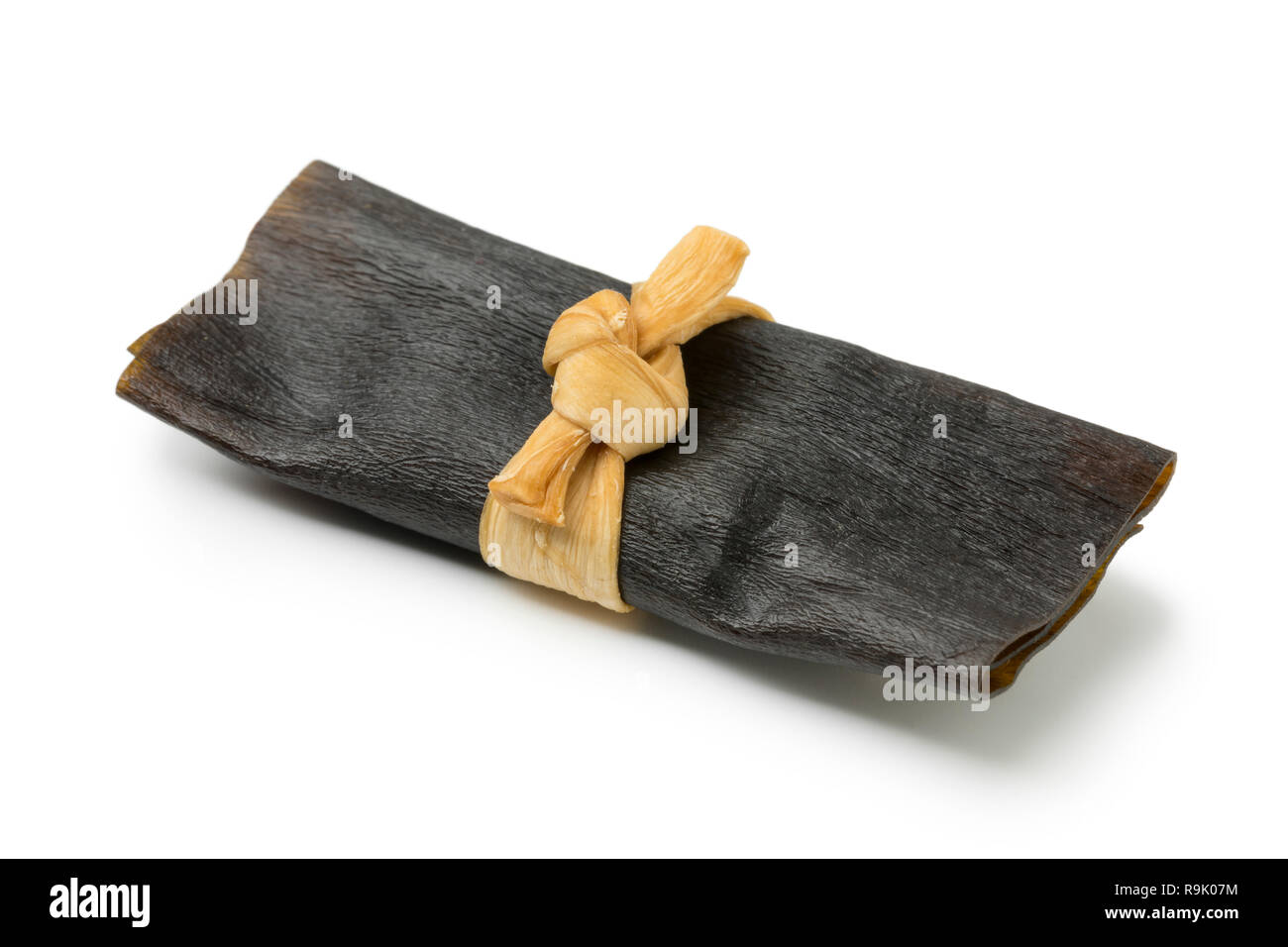 Single traditional dried and seasoned kelp roll, kobumaki, isolated on