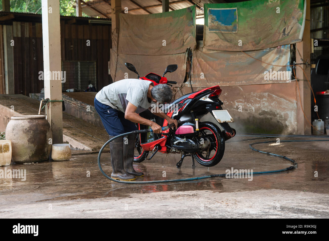 Old man wash your motorcycle with High Pressure Washer at car wash shop