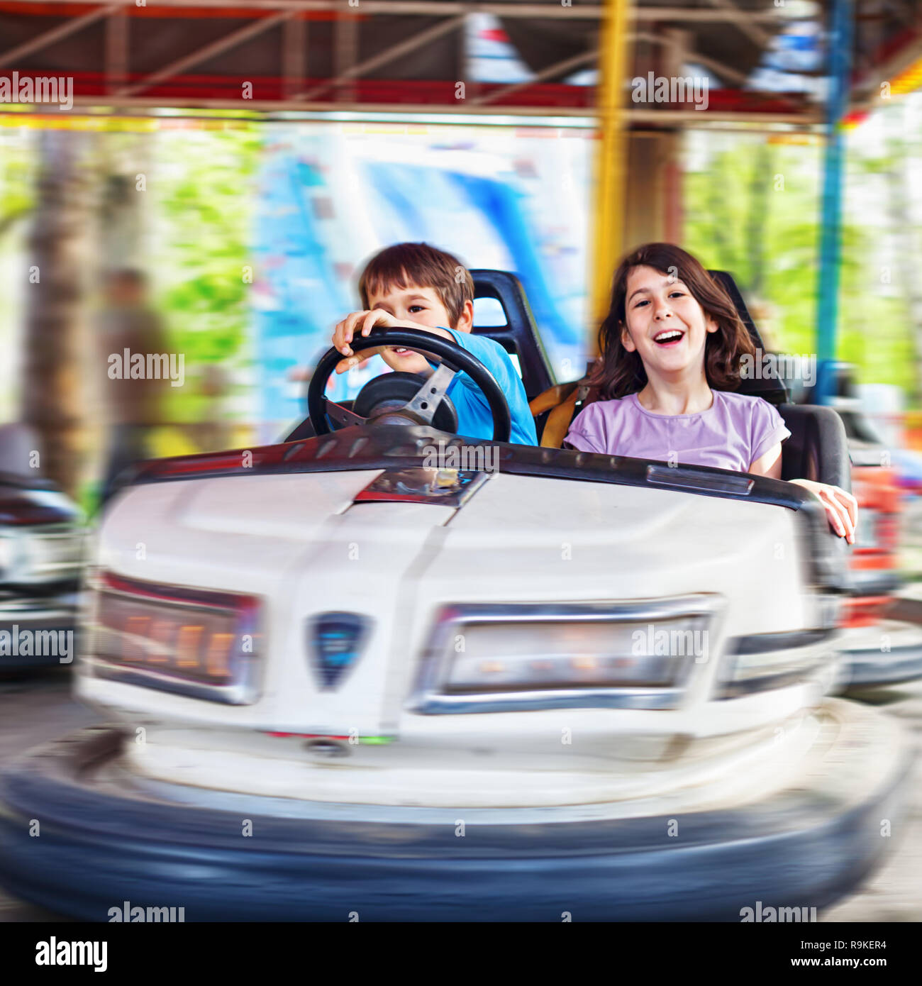 Two kids laughing, having fun driving a bumper car, motion blur Stock