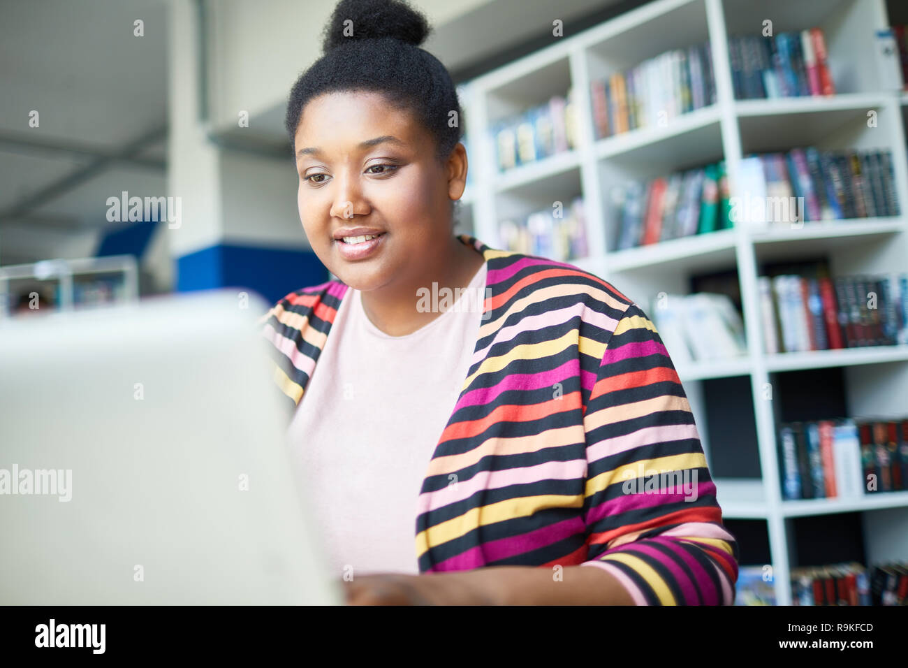 Cheerful African student reading online article Stock Photo - Alamy