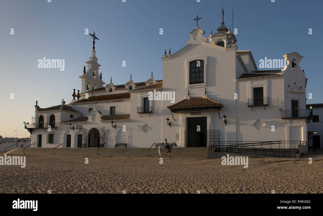 A man on a horse is praying in front of the Ermita de El Rocio church at the end of the day, El Rocio, Spain Stock Photo