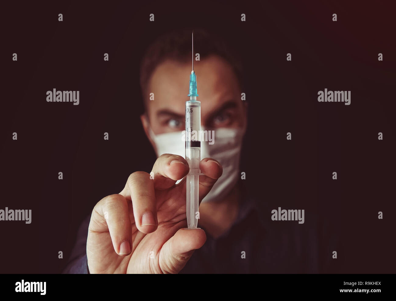 Out of focus doctor with syringe in a dark background. doctor keeps talking in the hands of a syringe with a medicine. Sultry doctor. Unskilled specia Stock Photo