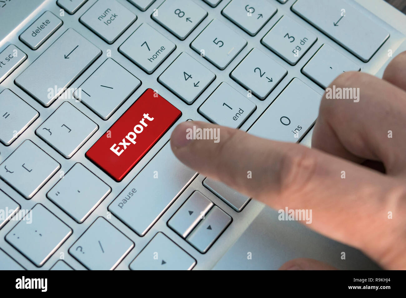 red key with text Export on white laptop keyboard. A male finger