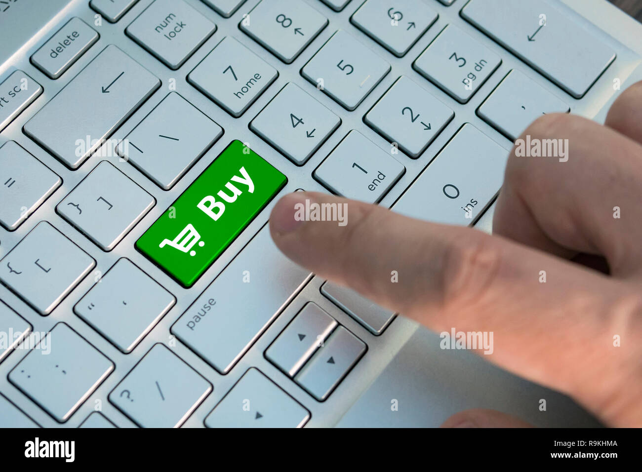 buy button on computer keyboard showing business concept. A male finger presses a color button on a gray silver keyboard of a modern laptop. Button wi Stock Photo
