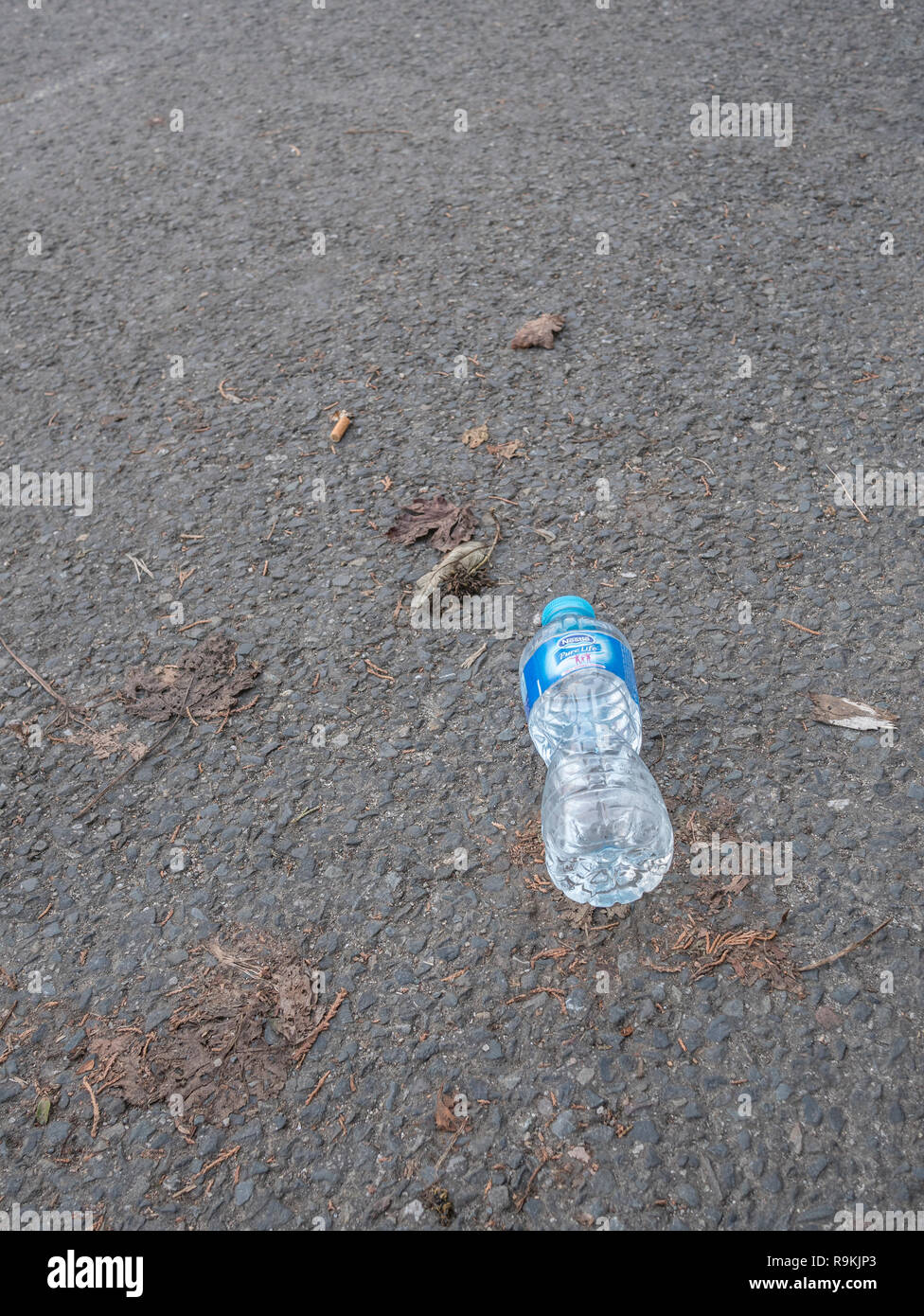 PTFE plastic mineral water bottle discarded in urban area. Metaphor plastic pollution, environmental pollution, war on plastic waste, plastic rubbish. Stock Photo
