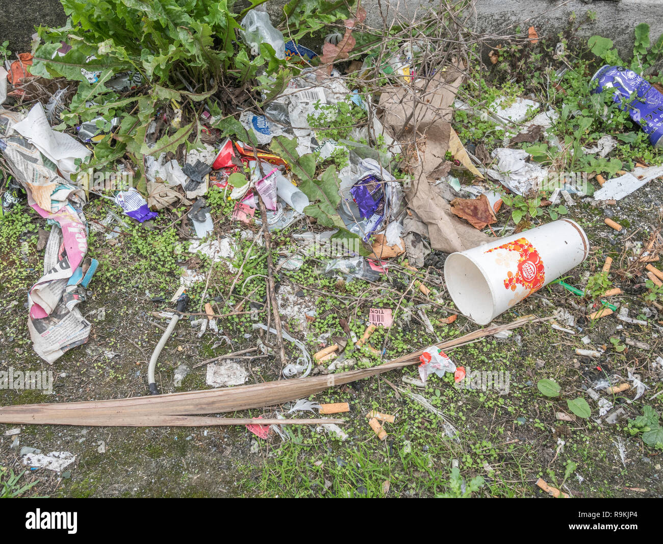 Plastic rubbish discarded in urban backstreet. For plastic pollution, war on plastic waste, plastic rubbish, takeaway food packaging. Stock Photo