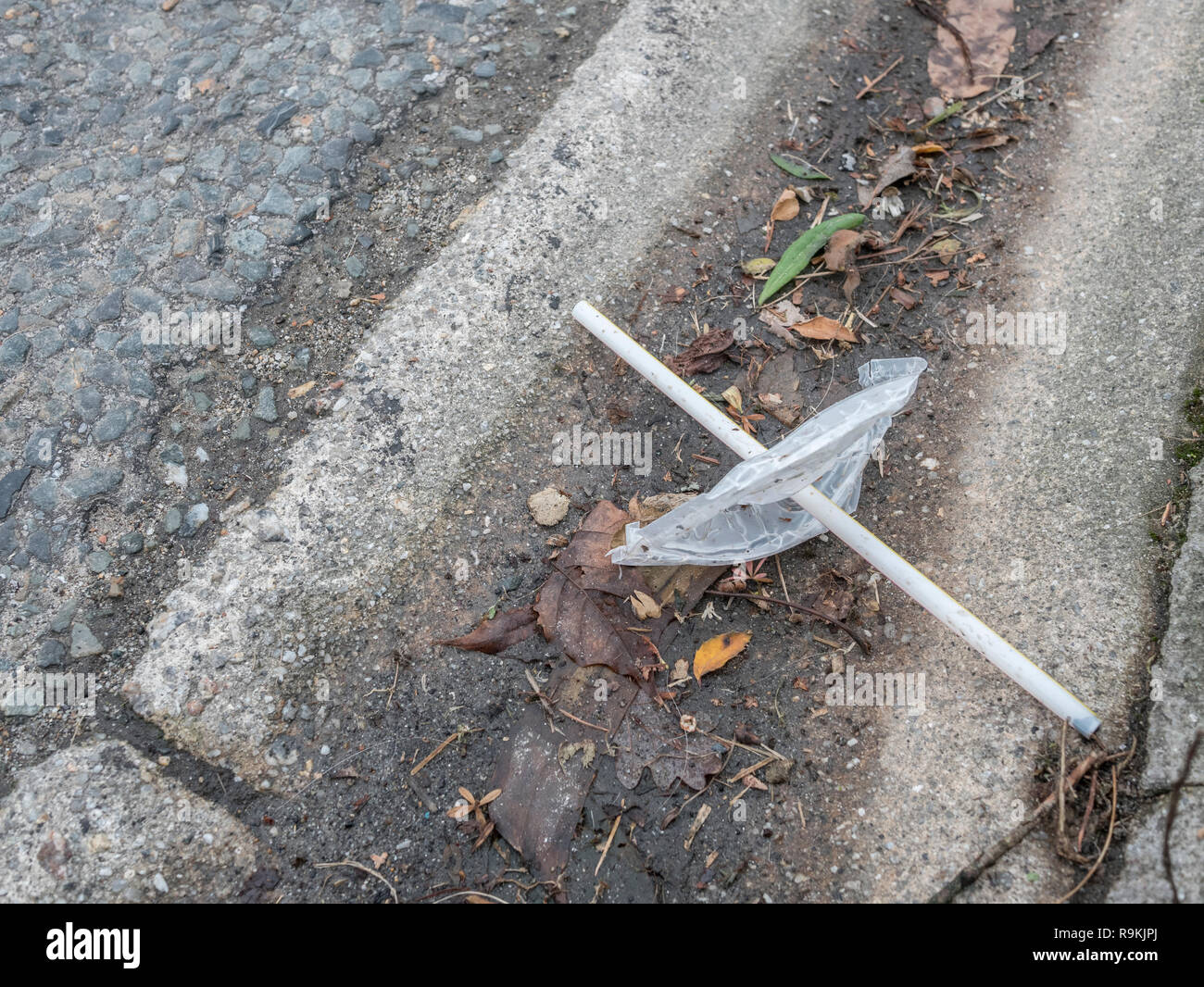 PTFE plastic soft drink cup top & plastic straw discarded in urban area. For environmental pollution, war on plastic waste, plastic straw ban. Stock Photo
