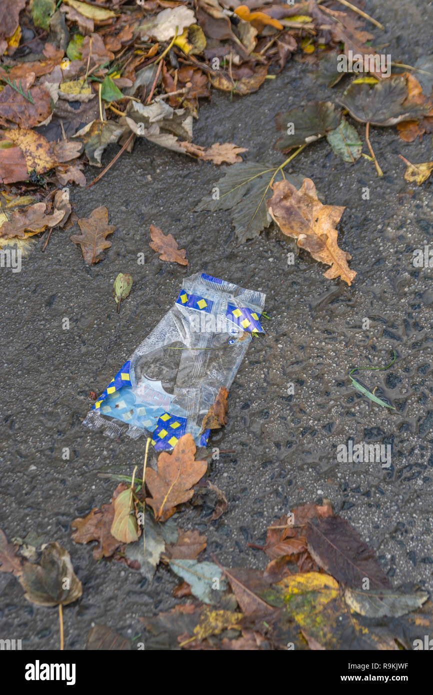 Plastic takeaway food wrapper discarded on rural country road. Metaphor plastic pollution, environmental pollution, war on plastic waste. Stock Photo