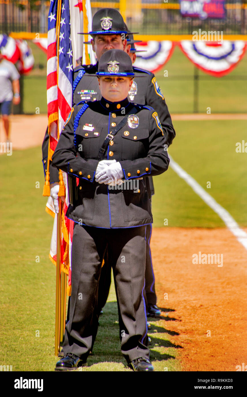 A stoical policewoman joins her male colleagues in dress uniform as they participate in the dedication of a softball stadium in Irvine, CA. Stock Photo