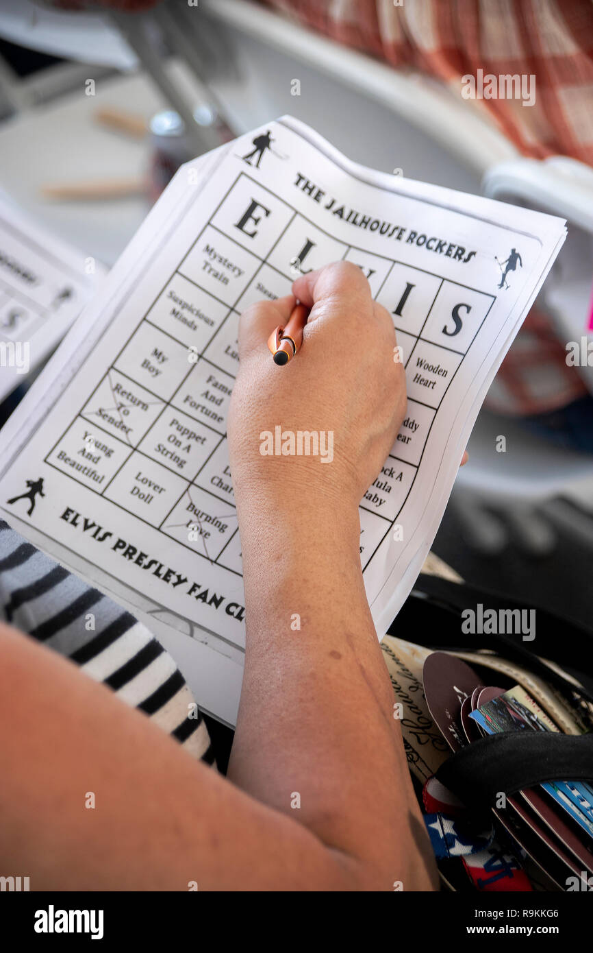 A woman in the audience at an Elvis Presley impersonation festival in Fullerton, CA, plays a specialized game of bingo based on Presley topics. Stock Photo
